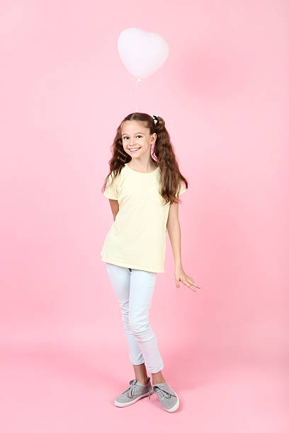 istock Cute young girl with balloon on pink background 2207371412