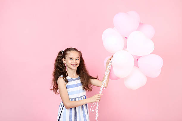 istock Young girl with balloons on pink background 2207373100