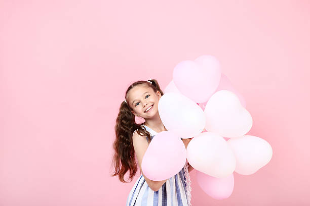 istock Young girl with balloons on pink background 2207373298