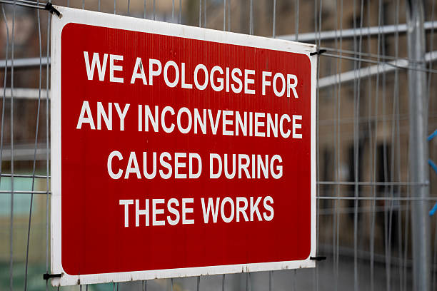 istock Red and White Construction Site Sign on Temporary Heras Fence Panel with Apology for Inconvenience Caused by Building Works 2207374012