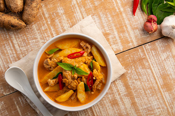 istock Thai red curry soup with pork and yam(Dioscorea esculenta yam),boiled sliced pork with red curry paste and coconut milk in white bowl.Top view. 2207376530