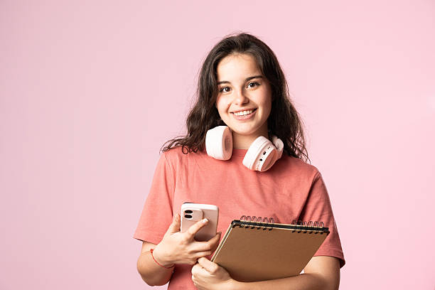istock Smiling student holding smartphone and notebook with headphones 2207377924