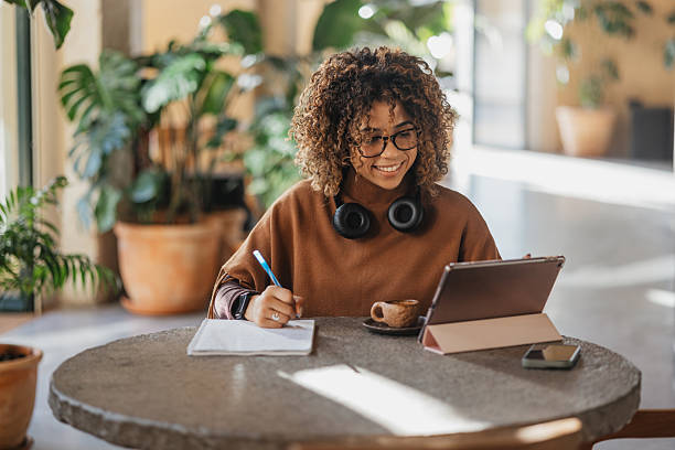 istock Woman Taking Notes on Tablet in Cafe 2207379116