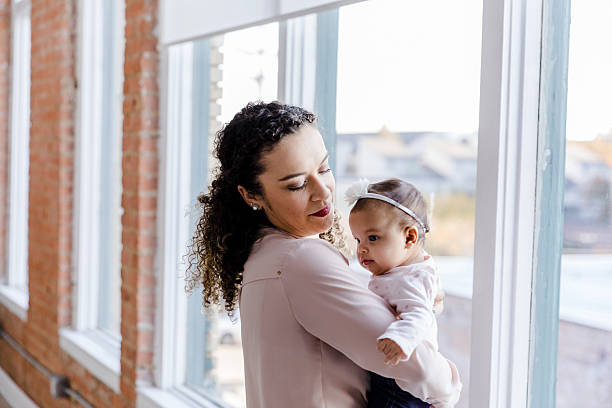 istock Affectionate Mother Holding Baby Near Window 2207379379