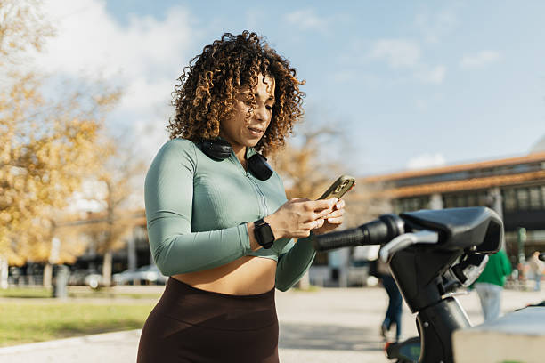 istock Smiling woman in activewear texting in a park. 2207379868