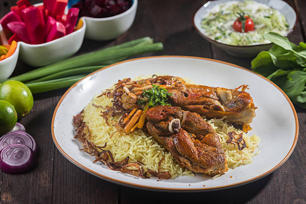 istock Mandi Rice with Meat served on a white plate features tender meat, aromatic rice, and various side dishes isolated on wooden table side view of a gourmet Arabian platter 2207380076