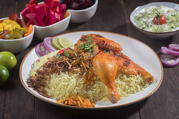 istock Chicken Machboos served on a white plate features roasted chicken, spiced rice, and various side dishes side view of gourmet Arabian meal 2207381150