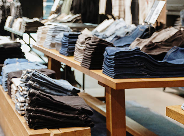 istock Blurred view of folded jeans and shirts on a shelf in a store. 2207388734