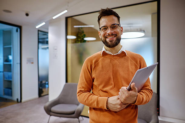istock Young businessman smiling in modern office holding a folder 2207394196