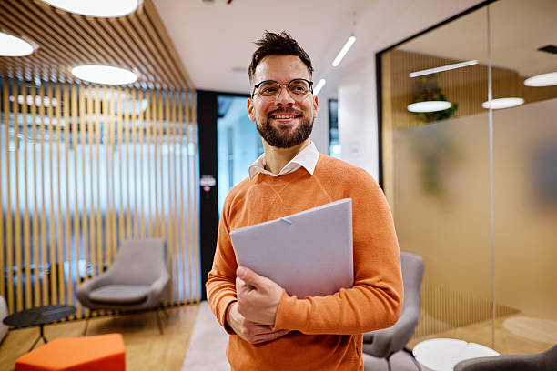 istock Young businessman holding documents and smiling in modern office space 2207394199