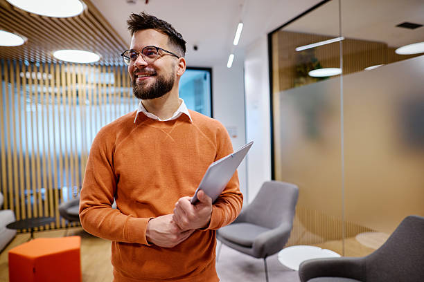 Young businessman smiling in modern office holding a folder
