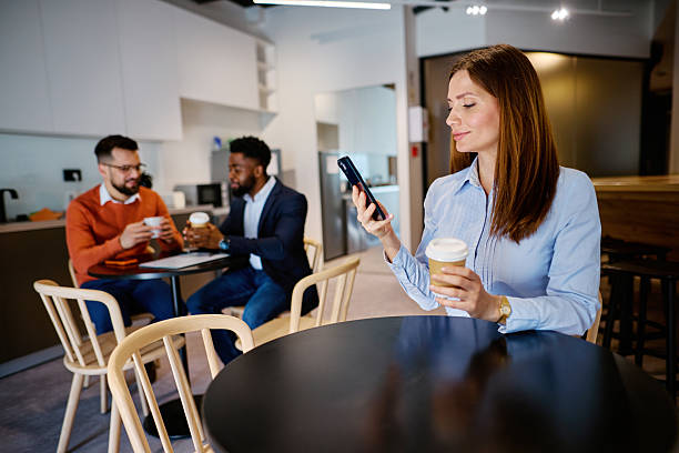 istock Businesswoman using smartphone and drinking coffee in modern office break room 2207394251