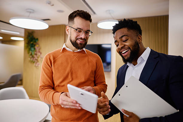 istock Two happy businessmen using digital tablet and clipboard in modern office 2207394366