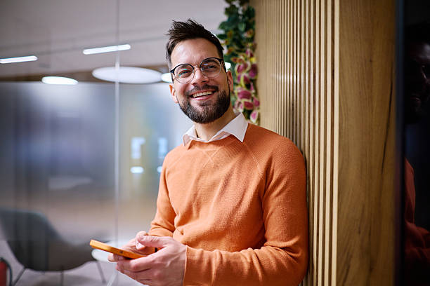 istock Young businessman smiling and using smartphone in modern office 2207394487