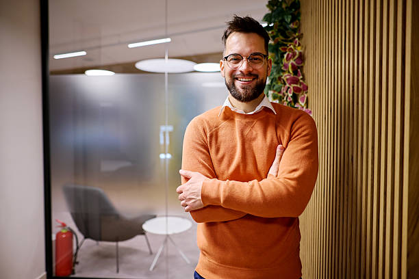 istock Confident businessman smiling with arms crossed in modern office 2207394492