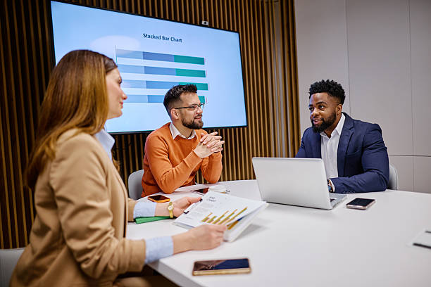 istock Business Team Discussing Charts and Data on Laptop in Modern Office 2207394719