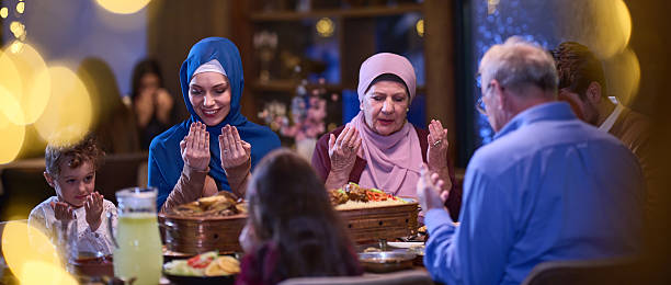 istock In a modern restaurant setting, a European Islamic family comes together for iftar during Ramadan, engaging in prayer before the meal, uniting tradition and contemporary practices in a celebration of faith and family 2207401686