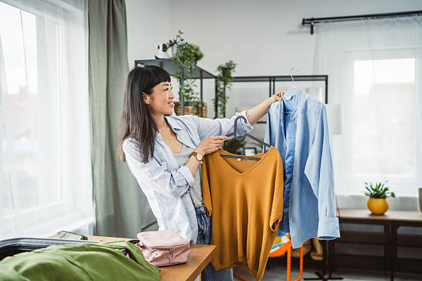 istock japanese woman hold two coat hangers with shirts ready to pack them 2207401865