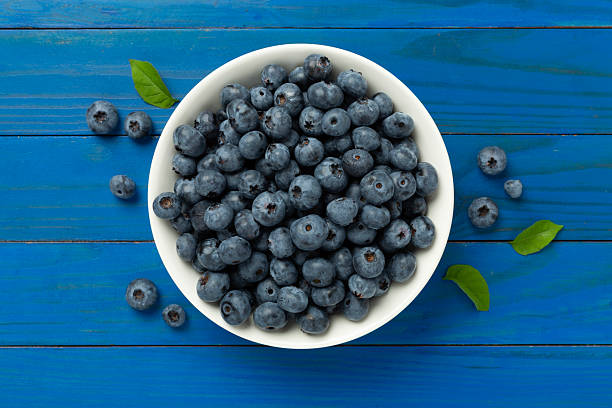 istock Bowl with fresh bright blueberries on wooden background,top view 2207401993