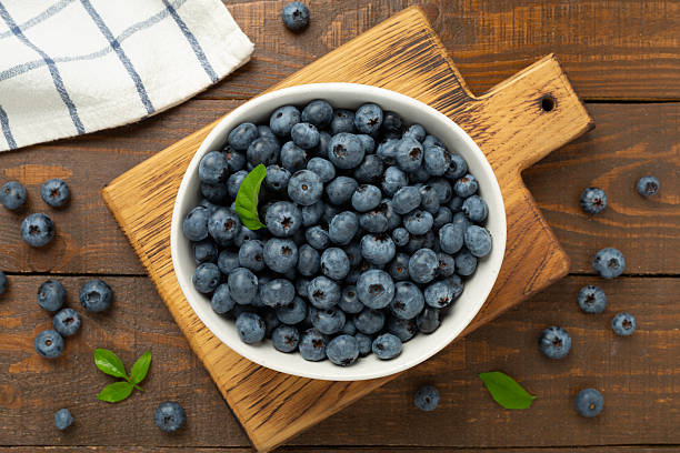 istock Bowl with fresh bright blueberries on wooden background,top view 2207402003