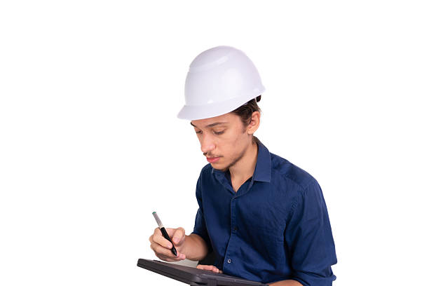 istock Young architect wearing white helmet, sitting, working with tablet. Isolated on white background. 2207402021
