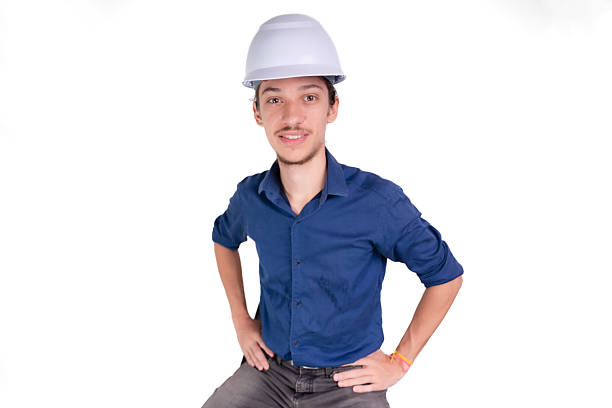 istock Studio portrait of young architect sitting wearing white helmet and looking at camera. Isolated on white background. 2207402025