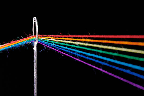 istock multi-colored threads for sewing in the form of a rainbow pass through an antique needle on a black background 2207402590