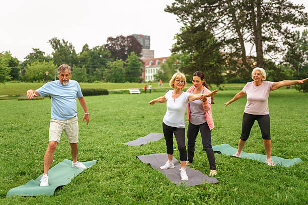 istock Senior Citizens and Instructor Enjoying Yoga in Park 2207413030