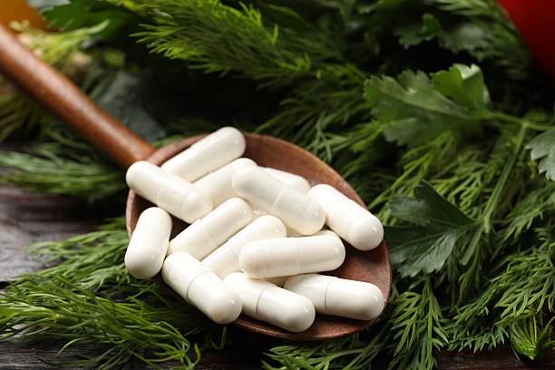 istock Dietary supplements. Spoon with pills, dill and parsley on table, closeup 2207413412