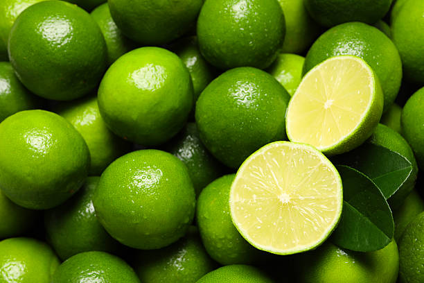 istock Fresh limes and leaves with water drops as background, top view 2207413492