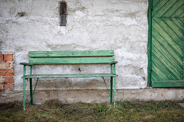 Green Bench and Door in Front of Weathered Wall.