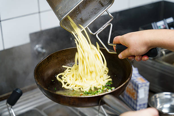istock Freshly cooked pasta being added to a pan with garlic and herbs 2207420841