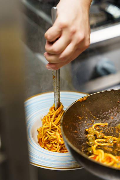 istock Chef using tongs to plate spaghetti with tomato sauce 2207420843