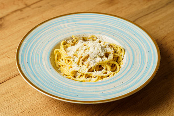 istock Classic spaghetti cacio e pepe with grated cheese on a blue-striped plate 2207420849