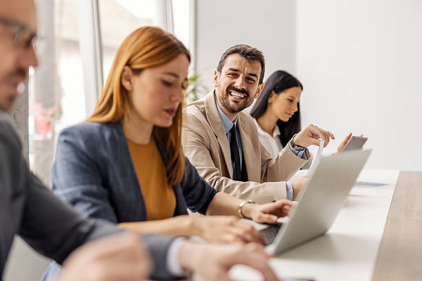 istock Young executive sitting at boardroom with his team and smiling while doing case study. 2207434058