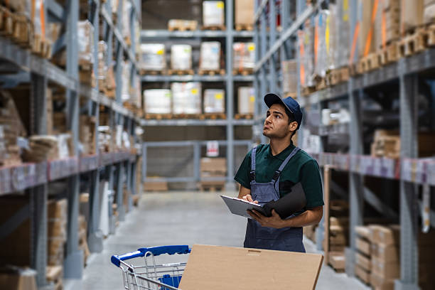 istock Warehouse worker checking inventory using clipboard and cart in a large distribution center 2207449114