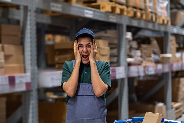 istock Young male warehouse worker looking shocked while holding his head in his hands 2207449287