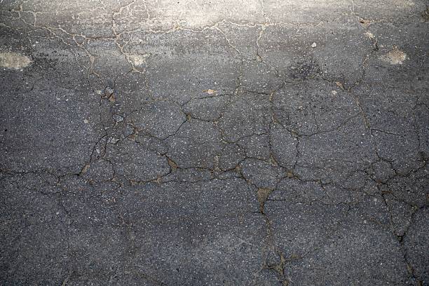 istock Cracked asphalt road surface with large fractures, urban grunge texture background 2207457561