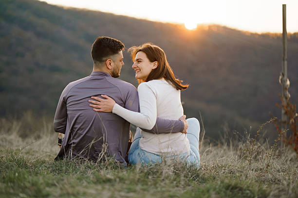 istock Happy couple sitting on a hill during sunset 2207459293
