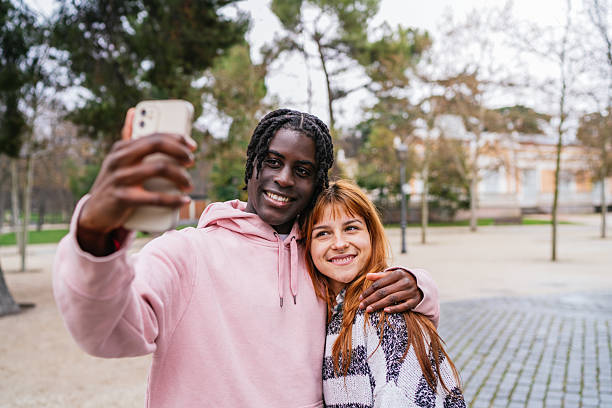 istock Young multiracial couple taking a selfie in the park 2207459311