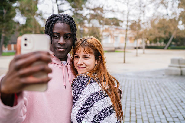istock Young multiracial couple taking a selfie in the park 2207459322