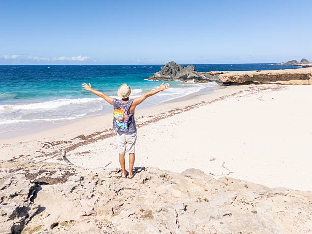 istock Man with straw hat enjoying a sunny day on a scenic rocky beach 2207462326