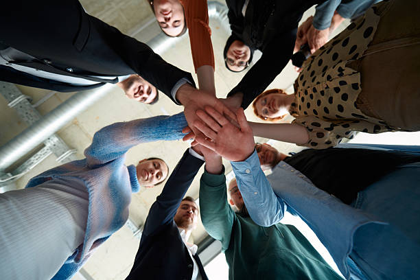 istock A group of business professionals, captured from a low angle, holding hands to symbolize unity and teamwork. 2207465479