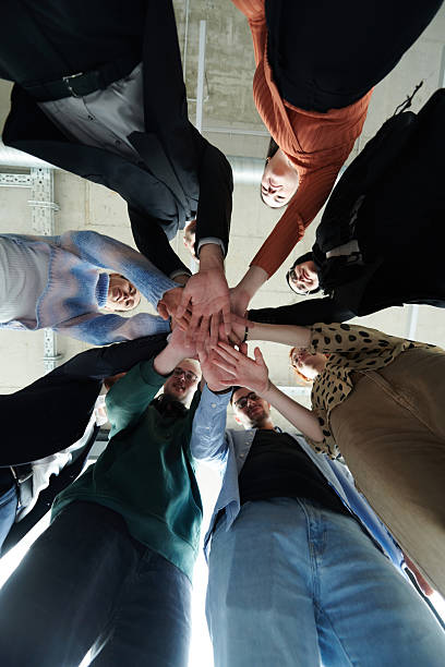 istock A group of business professionals, captured from a low angle, holding hands to symbolize unity and teamwork. 2207465573