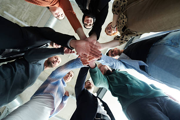 istock A group of business professionals, captured from a low angle, holding hands to symbolize unity and teamwork. 2207465622