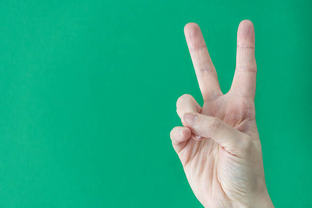 istock Hand gesturing peace sign against green background 2207465851