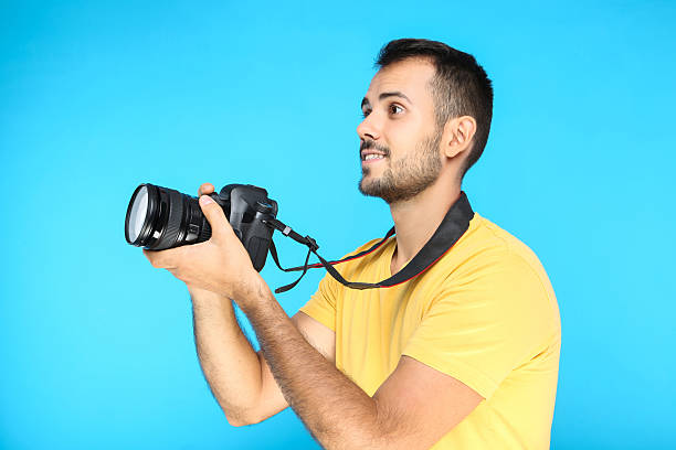 istock Young photographer with camera on blue background 2207467631