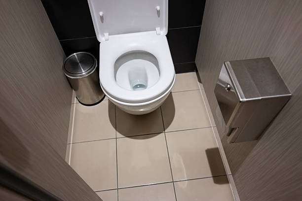 White ceramic toilet bowl with lid open in a clean bathroom. Essential hygiene fixture in a tiled restroom for residential or public use.