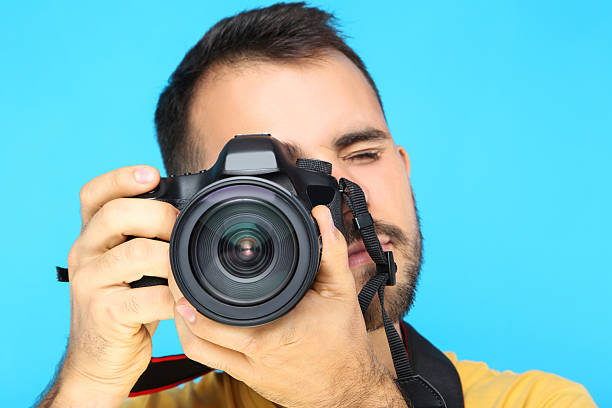 istock Young photographer with camera on blue background 2207468635