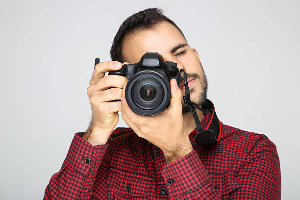 istock Young photographer with camera on grey background 2207468912